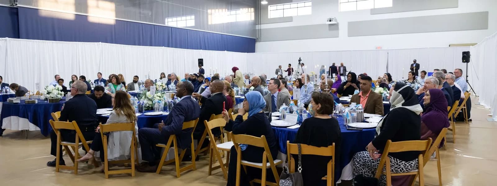 Guests at round tables during a community dinner in the EPIC hall